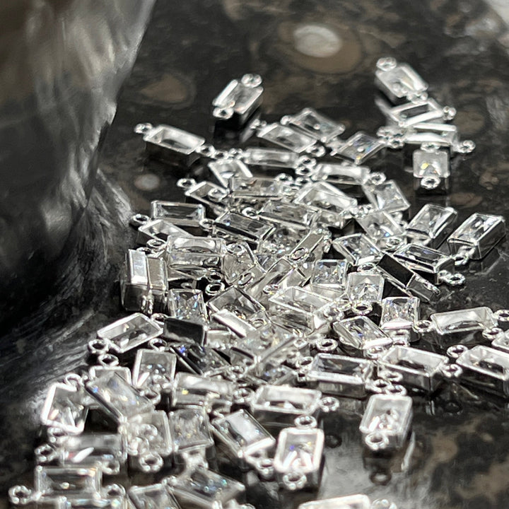 Close-up of clear CZ rectangle connectors on a textured surface