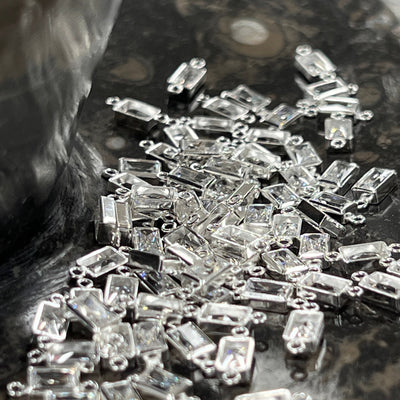 Close-up of clear CZ rectangle connectors on a textured surface