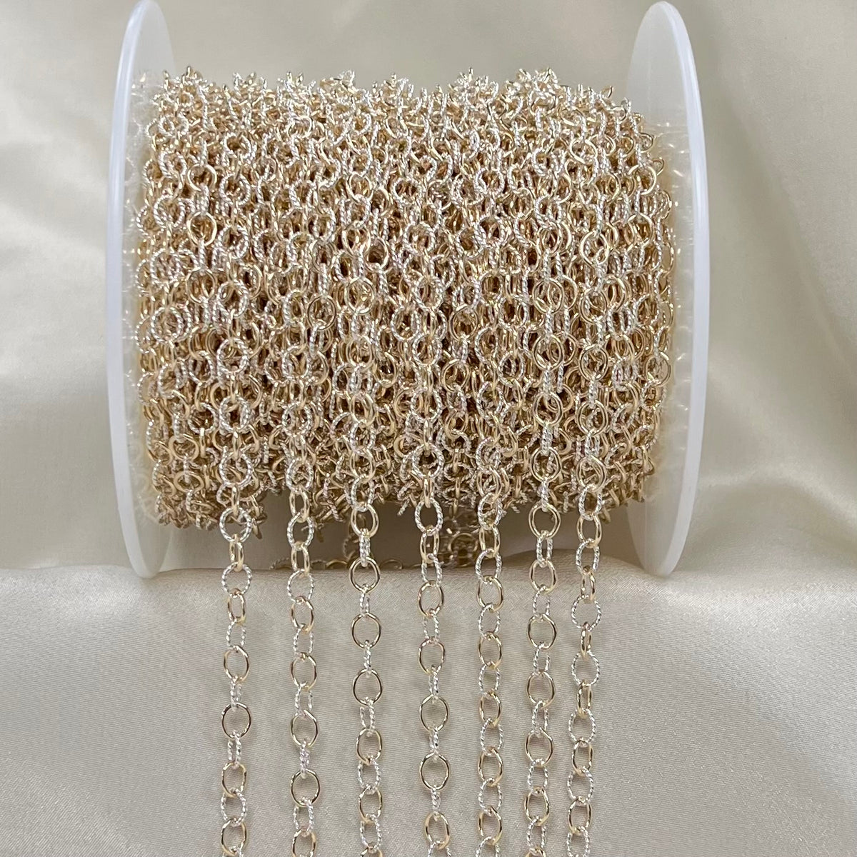 Spool of silver and gold chain on a white background
