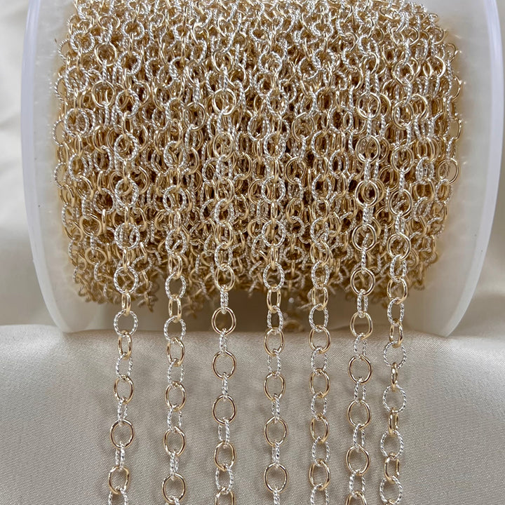 Spool of gold and white cable chain on a white background