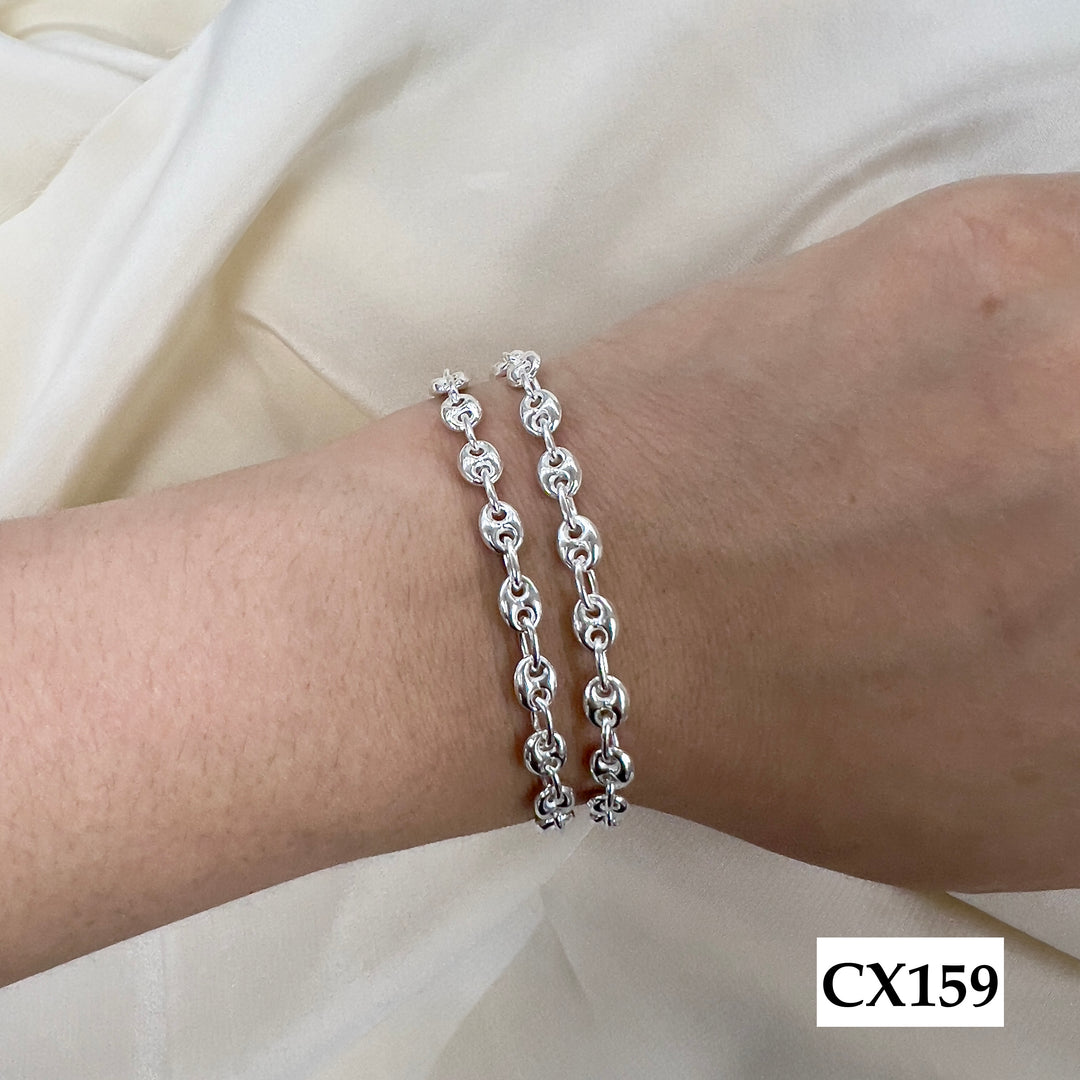 Silver chain bracelet on a wrist with a plain background