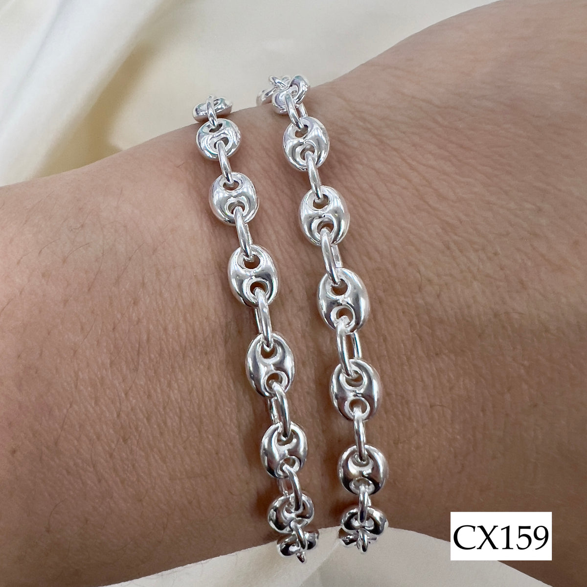 Silver chain bracelet on a wrist with a neutral background