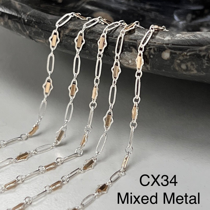 Mixed metal chain necklace on a textured surface with &
