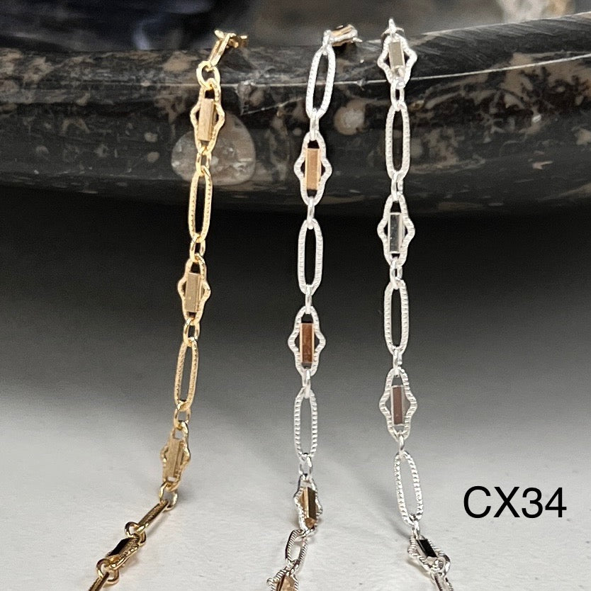 Two gold and silver chain necklaces on a dark stone surface.