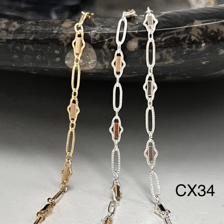 Two gold and silver chain necklaces on a dark stone surface.
