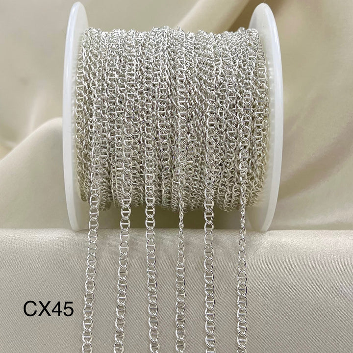 Spool of silver chain on a beige background