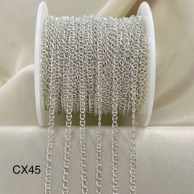 Spool of silver chain on a beige background
