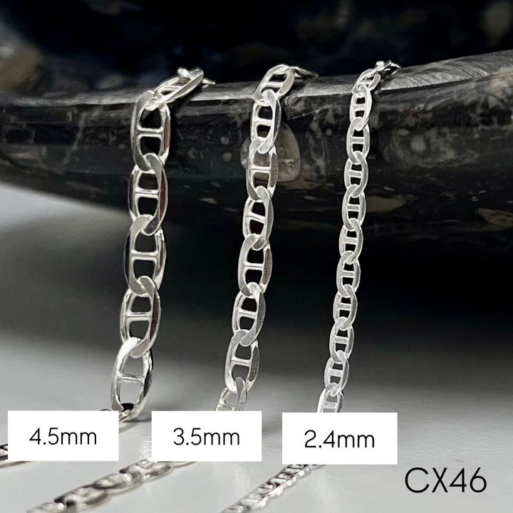 Three silver mariner chain necklaces of different widths on a dark background